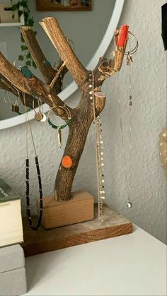 a wooden tree with necklaces hanging from it's branches in front of a mirror