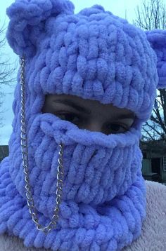 a close up of a person wearing a knitted animal hat and scarf with chains