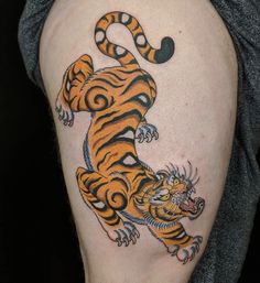 a man with a tiger tattoo on his arm and leg, holding onto the tail of a