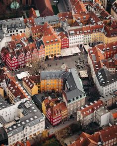 an aerial view of several buildings in a city with red roofs and brown roof tops