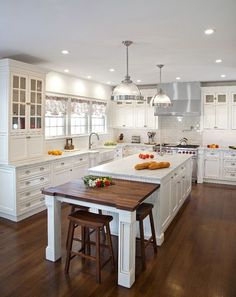 a large kitchen with white cabinets and wooden floors