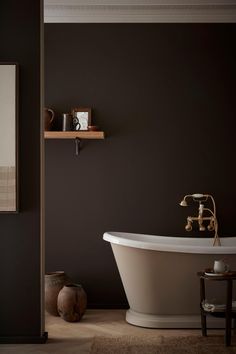 a bath tub sitting next to a wooden shelf in a black and white bathroom with an old fashioned faucet