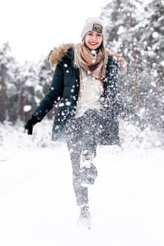 a woman is walking through the snow in winter