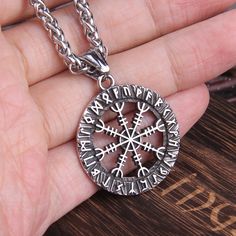 a person holding a compass necklace in their hand