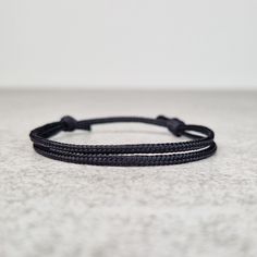 Simple black string bracelet, made from a nylon cord. The bracelet has an adjustable size thanks to the sliding knot. This a simple fabric jewelry that can be worn alone or stacked with other bracelets. Suitable for both men and women. The bracelet is fully water-resistant, so you can swim and shower with it. - - - - - - - - - - Materials: Nylon cord  - Cord diameter 2mm - Color: Black - - - - - - - - - Sizes: S - Fully Closed - 5.9"inches (15cm) / Full Opened - 11.8"inches (30cm) M - Fully Clos Adjustable Sliding Knot Nylon Thread Bracelets, Adjustable Black Band Friendship Bracelets, Black Bracelet With Sliding Knot For Beach, Adjustable Black Band Friendship Bracelet, Black Nylon Cord Braided Bracelet For Everyday, Everyday Black Braided Nylon Bracelets, Casual Black Wristband For The Beach, Casual Black Wristband For Beach, Gift Black Braided Bracelets With Adjustable Cord