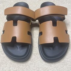 Herms Brand New, Unworn Men's Chypre Sandals - Gold - Size 43 W/Box Always Sold Out And Completely Impossible To Get These Days. Same As Bkc Quota Bags Almost. Lol. Seriously Though - Amazing Brand New Comfortable, Trendy, Stylish But Classic And New Timeless Statement Sandals Coveted And Hard To Get Noir Calfskin Leather With Soft Suede Bottom New With Box & Dustbags Iconic Sandals Instantly Recognizable H Logo Design Never Worn, Purchased Recently But Moving & Don't Need Anymore. Techno-Sandal Designer Brown Slides With Cushioned Footbed, Designer Brown Slides With Leather Footbed, Designer Leather Slides In Brown, Luxury Brown Slides With Round Toe, Designer Brown Leather Slides, Designer Brown Sandals With Cushioned Footbed, H Logo Design, Statement Sandals, H Logo