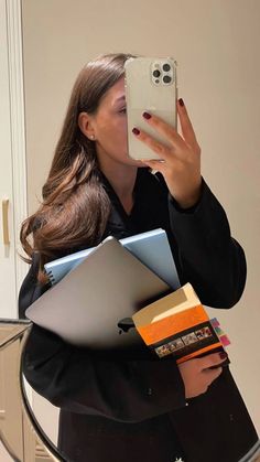 a woman taking a selfie in front of a mirror with books and notebooks