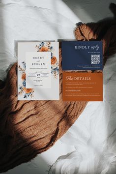 an orange and blue wedding suite on top of a white bed with a brown blanket