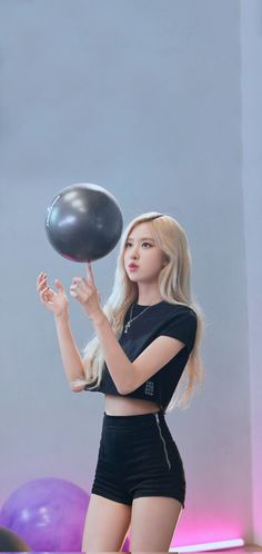 a woman in short shorts is holding a black ball and posing for the camera with her right hand