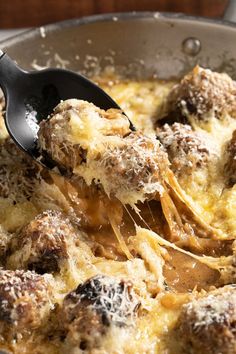 a ladle full of meatballs and cheese being stirred with grated parmesan cheese