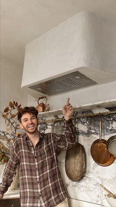 a man standing in front of an oven pointing to the ceiling with his finger up