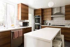 a kitchen with wooden cabinets and white counter tops, along with an island in the middle