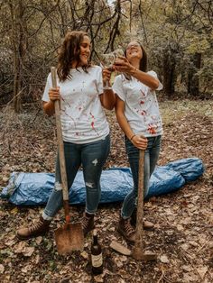 two women standing in the woods holding shovels