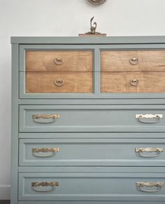 a blue dresser with drawers and a clock on the wall above it in a room