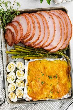 ham, eggs and asparagus are on a tray with other food in it