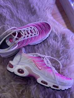 two pairs of pink and white sneakers on a furry rug in front of a window