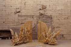 two wooden chairs sitting next to each other in front of a brick wall with flowers