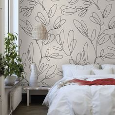 a white bed sitting next to a wall with plants on it