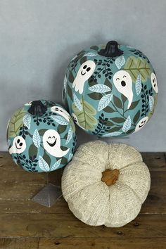 three painted pumpkins sitting on top of a wooden table