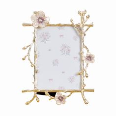 a white and gold frame with flowers on the front is hanging from a metal hook