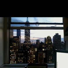 a laptop computer sitting on top of a desk in front of a window overlooking the city