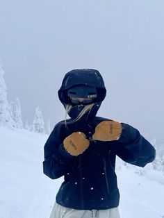 a person standing on top of a snow covered slope wearing skis and mittens