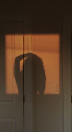 the shadow of a woman standing in front of a door with her hand on her head