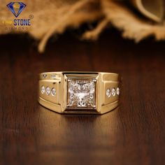 a gold ring with a princess cut diamond set in the center on a wooden surface