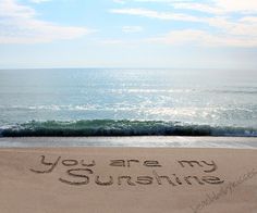 the message you are my sunshine written in sand at the edge of the ocean with waves