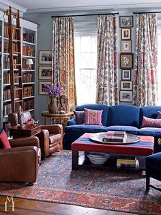 a living room filled with furniture and bookshelves next to a window covered in curtains