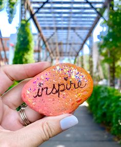 someone holding up a rock with the word inspire written on it