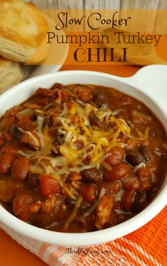 slow cooker pumpkin turkey chili in a white bowl on an orange napkin with bread