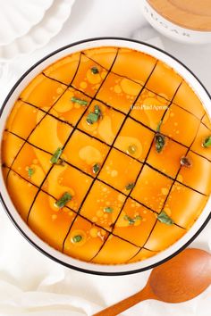 an orange cake with green toppings in a white bowl on top of a table