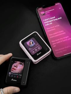 two cell phones sitting next to each other on top of a black table with pink background