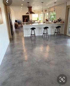 an empty kitchen and living room are seen in this image with stools on the floor