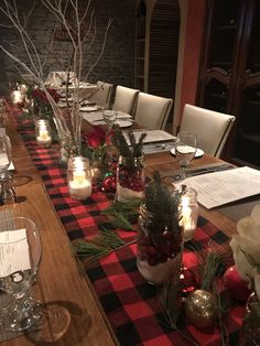 a long table is set with christmas decorations and candles for the centerpieces, along with place settings