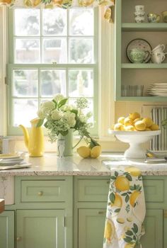 a kitchen with green cabinets and lemons in the window sill on the counter