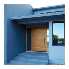 a wooden door in front of a blue building with steps leading up to the entrance