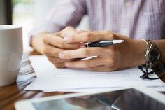 a person sitting at a table with a pen and paper in front of their hands