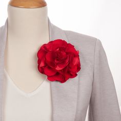 a woman wearing a gray jacket and red flower brooch on her lapel collar