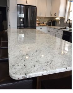 a kitchen counter top with white cabinets and black appliances in the backgrounnd