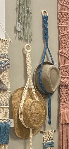 several hats hanging up on a wall next to some yarns and other items that have been hung from hooks