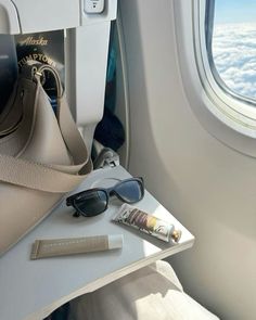 an airplane seat with sunglasses and a purse on it next to the window sill