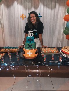 a woman standing in front of a table with cakes and cupcakes on it