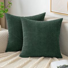 two green pillows sitting on top of a white couch next to a potted plant