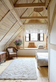 an attic bedroom with wooden floors and white walls, along with a large rug on the floor