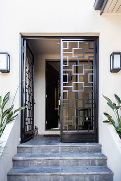 an entrance to a home with black iron doors and decorative designs on the front door