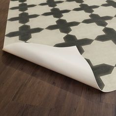 a white rug with black and grey designs on the floor next to a wooden floor