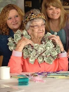 three women sitting at a table with money in front of them and one woman standing behind her