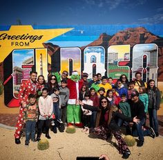 a group of people standing in front of a sign that says greetings from arizona